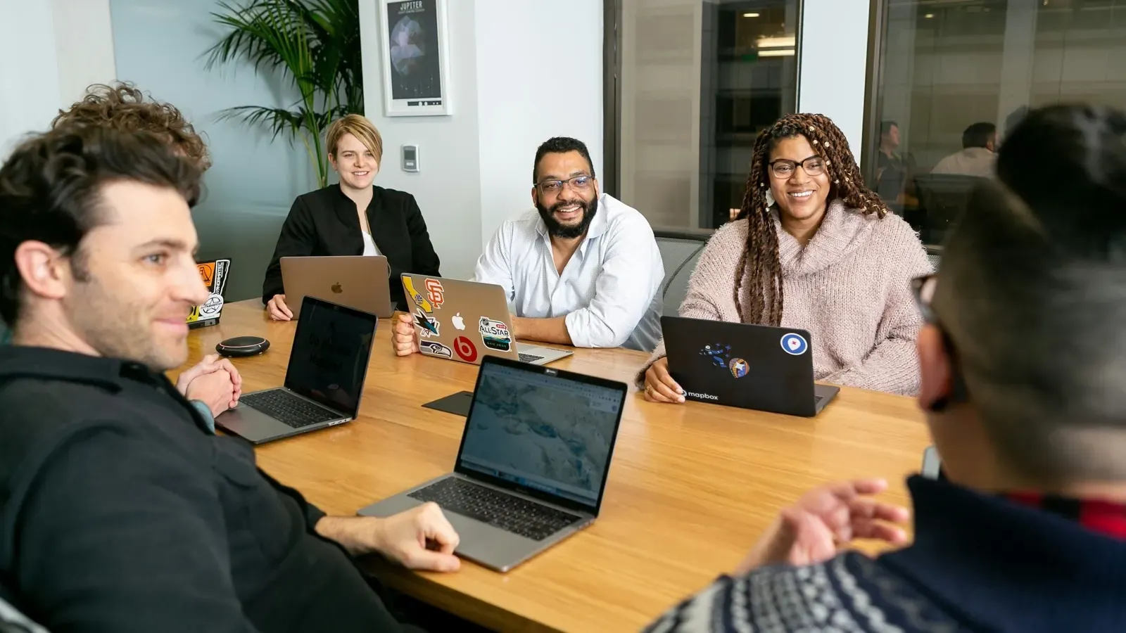 A team meeting around a table with laptops open