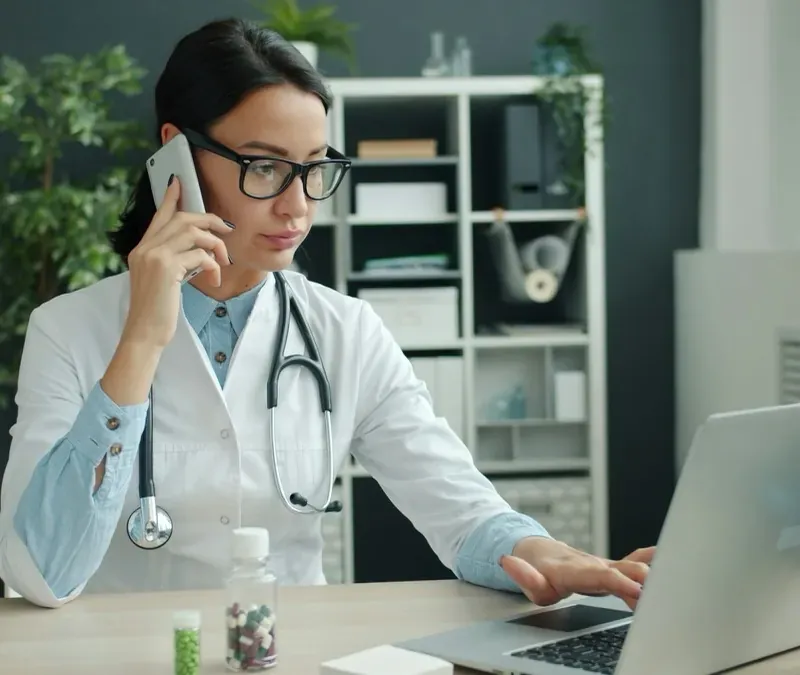 An administrator taking a call at a screen in a clinic office