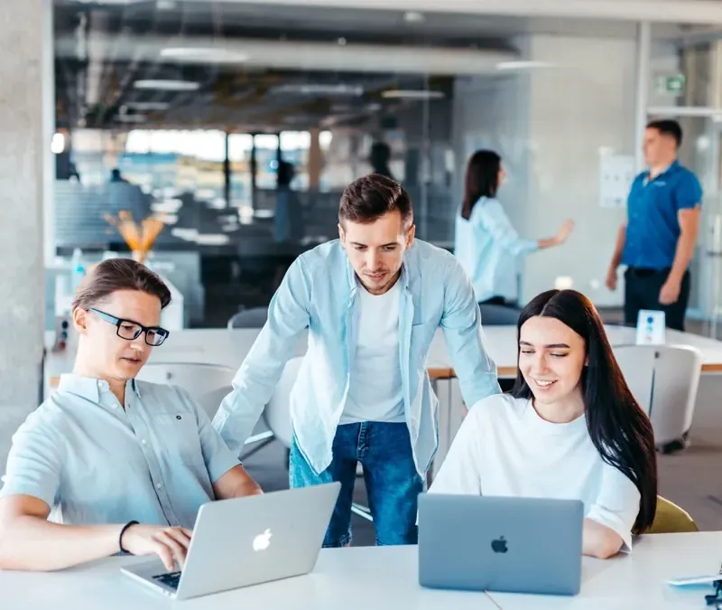 Three colleagues working through a task together on laptops