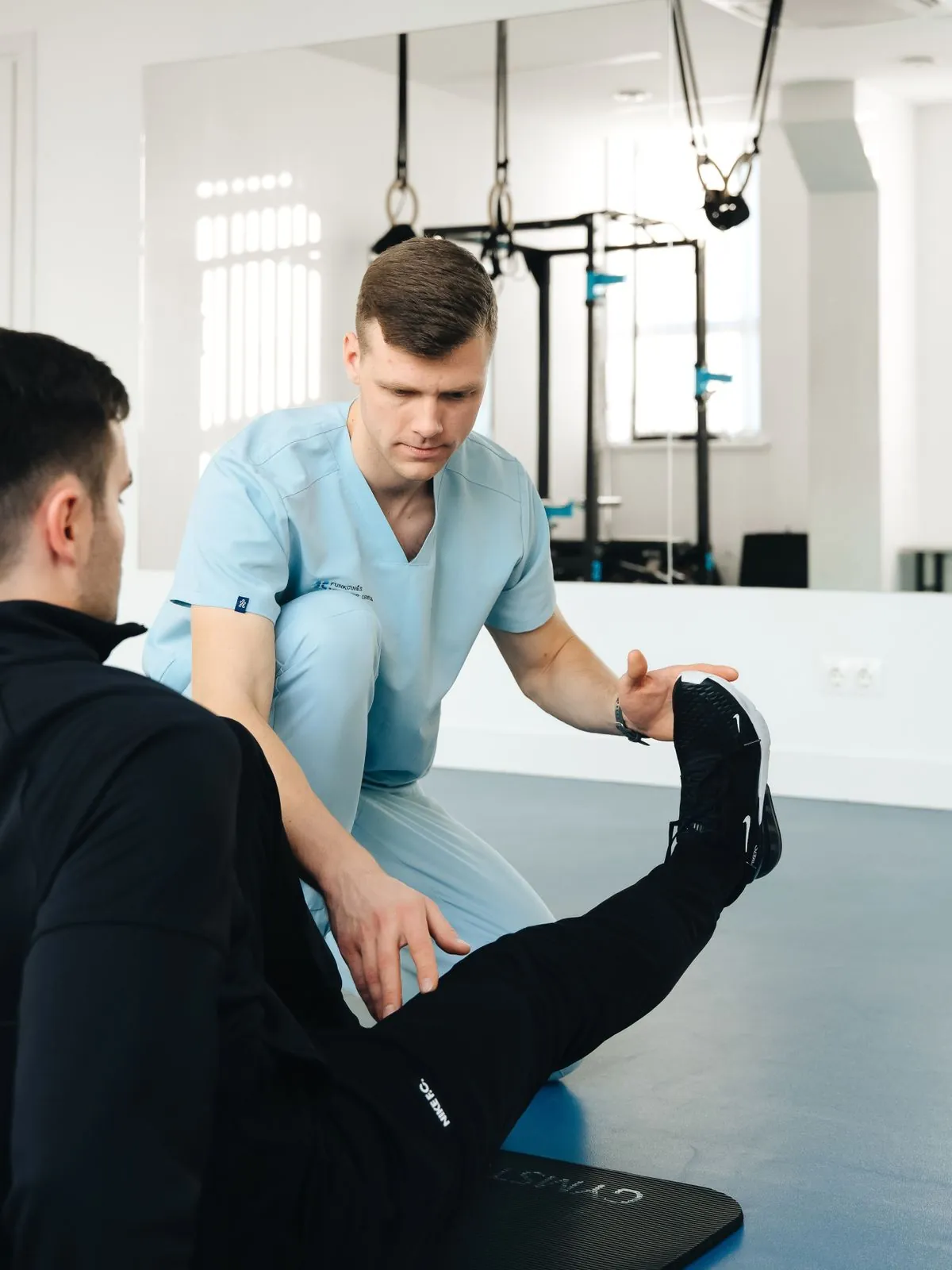 A physiotherapist guiding a patient through a leg stretch in a clinic